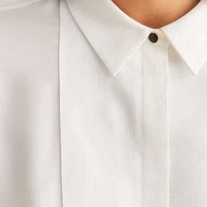 To complement V-neck knits and tucked-in styling with high waistlines, the placket is crafted from contrasting pure cotton.