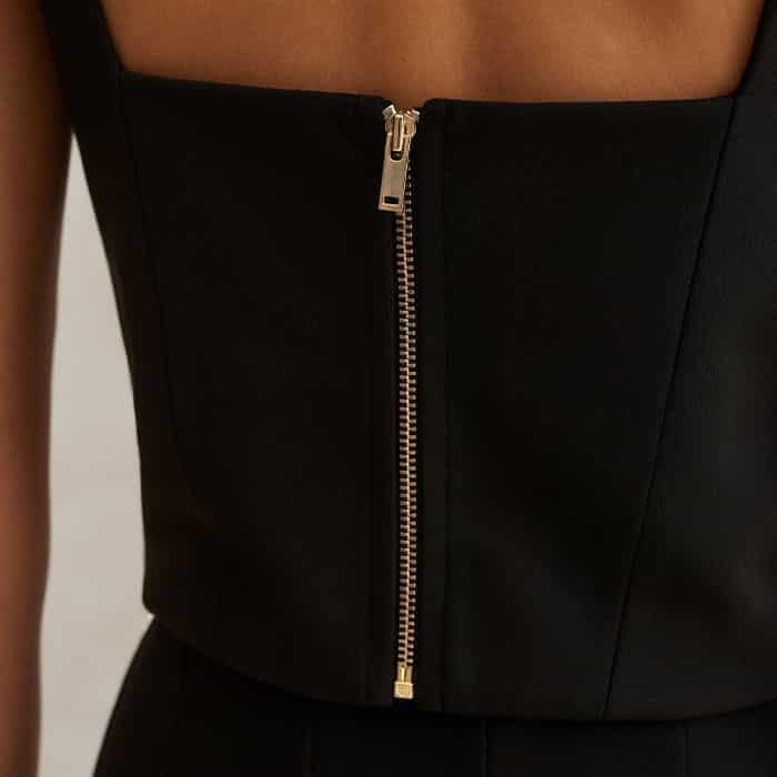 The gold-toned zip fastening at the back is an integral design detail that doubles as a key focal point. 