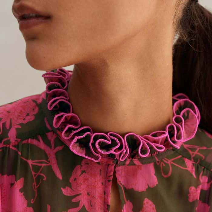 Outlining the top of the neckline, ruffle trims highlight the tiered construction and sign off the long sleeves fitted with elastic at the cuffs.