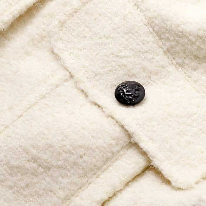 Italian bouclé fabric woven with alpaca to give it a lofty look. Features contrast glossy black Italian buttons.