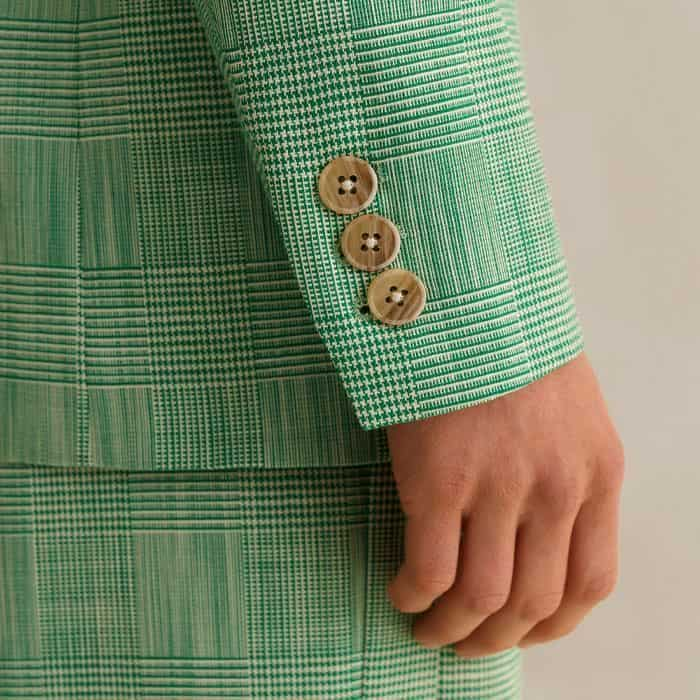 The cuffs are decorated with three contrasting kissing buttons.