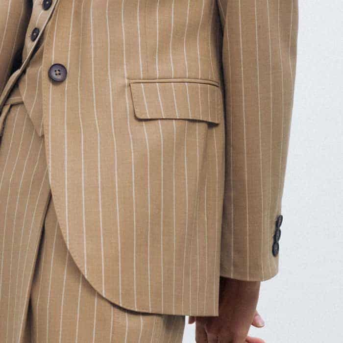 Topped with flaps and subtle piping, deep pockets are positioned on either side of the button-down front.