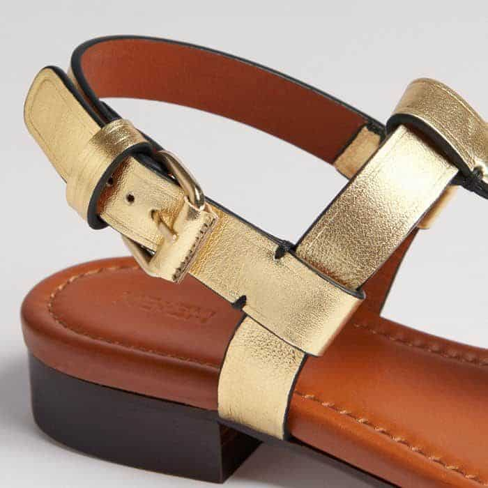 The gold-plated hardware features a leather-covered roller buckle.