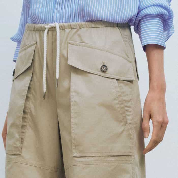 The oversized pockets are detailed with a contrasting button to add functionality to the piece.