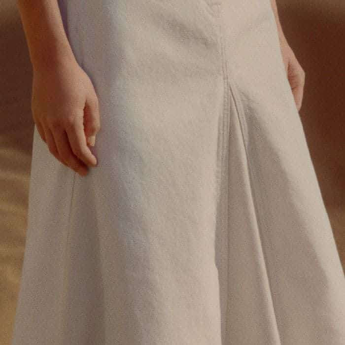 Contrasting ecru pleats add definition to the silhouette.