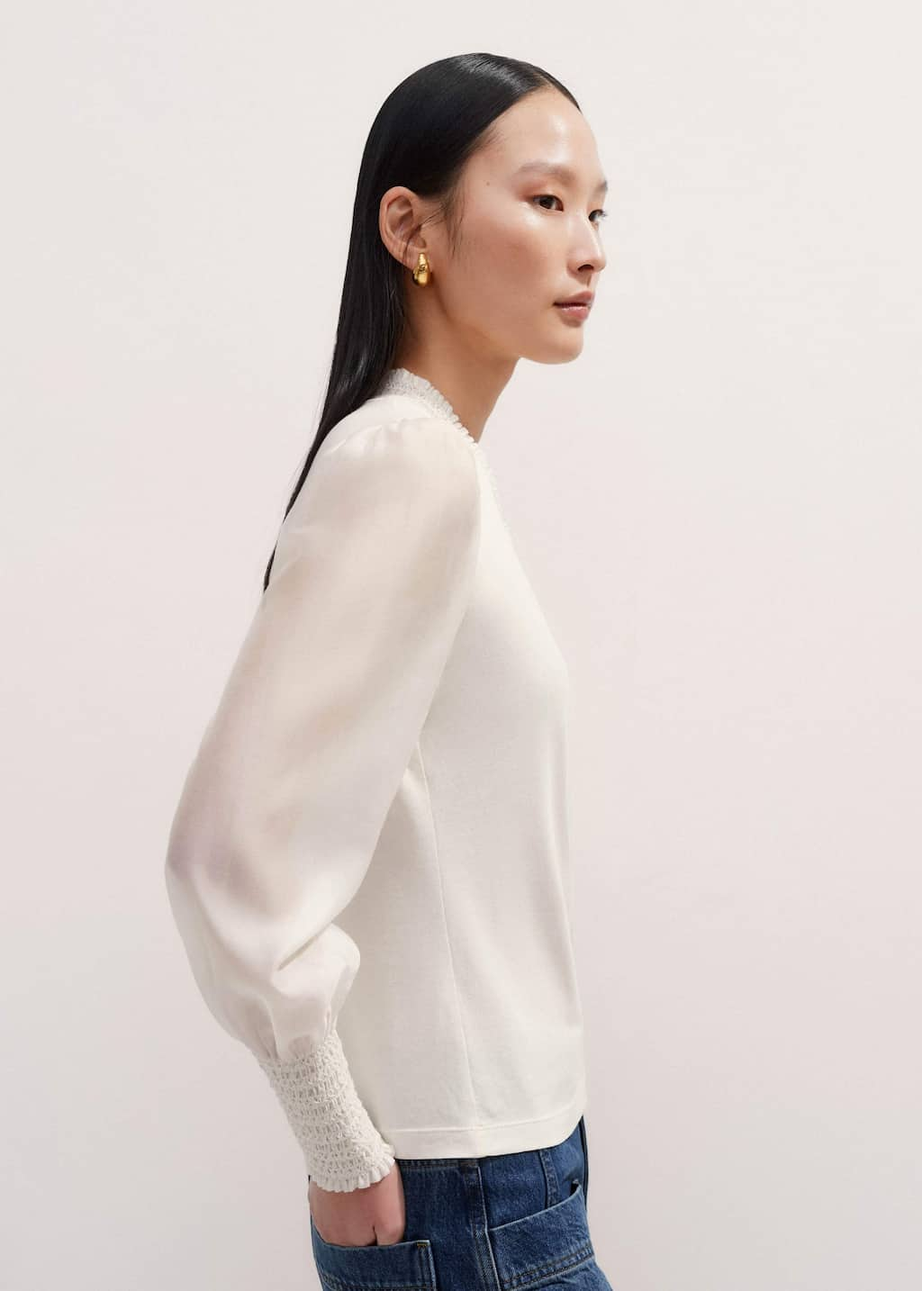 The V-neckline is lined with a ruffled trim that can be left on display when the piece is worn under complementary knits.