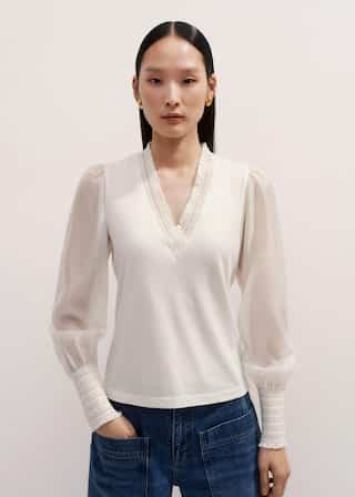 The V-neckline is lined with a ruffled trim that can be left on display when the piece is worn under complementary knits.