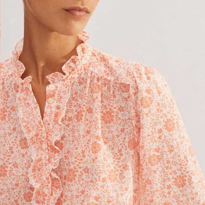 The placket is elevated with a ruffled trim for a feminine finish. 