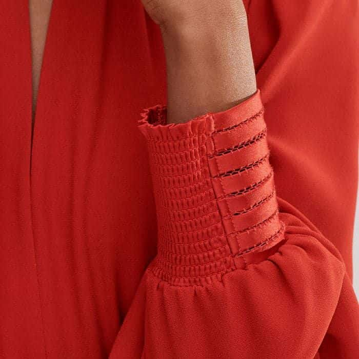 The half-shirred fitted cuffs enhance the voluminous shape of the sleeves.