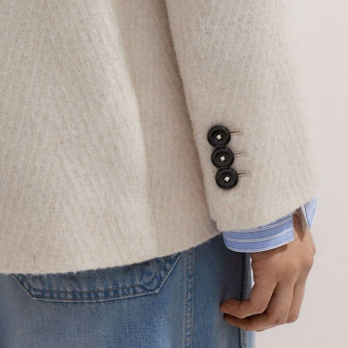 The cuffs are lined with contrasting black kissing buttons.