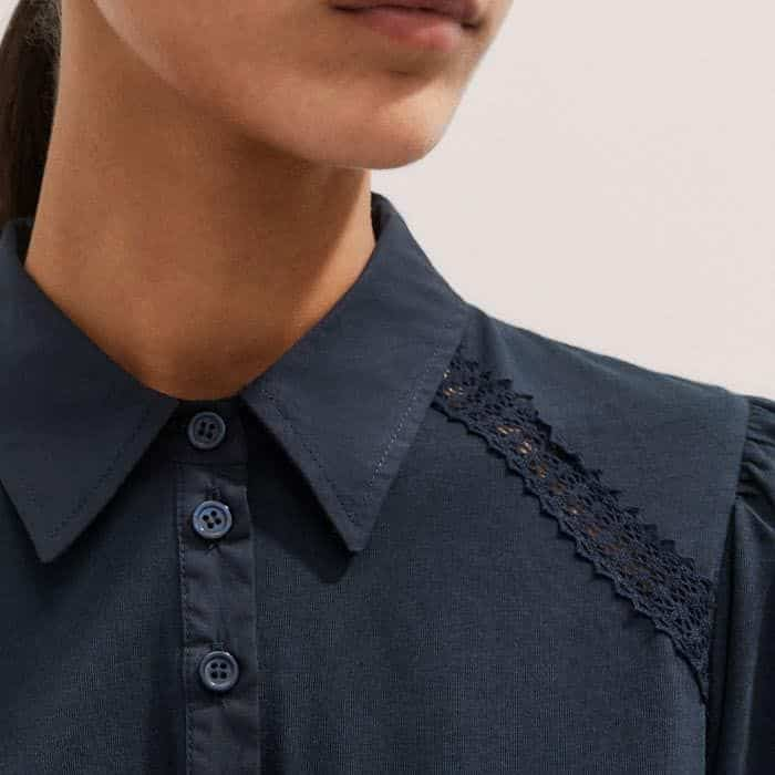 Contrasting lace trims at the shoulders and sleeves introduce a feminine touch to the piece.