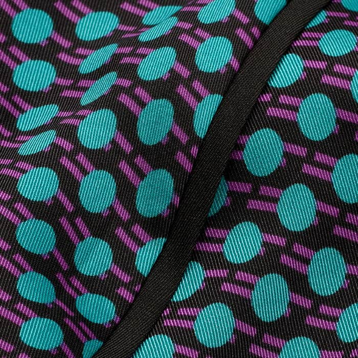 Our bespoke Digital Dot print in green and purple on a black base covering high-shine satin with a lustrous finish and fluid drape.